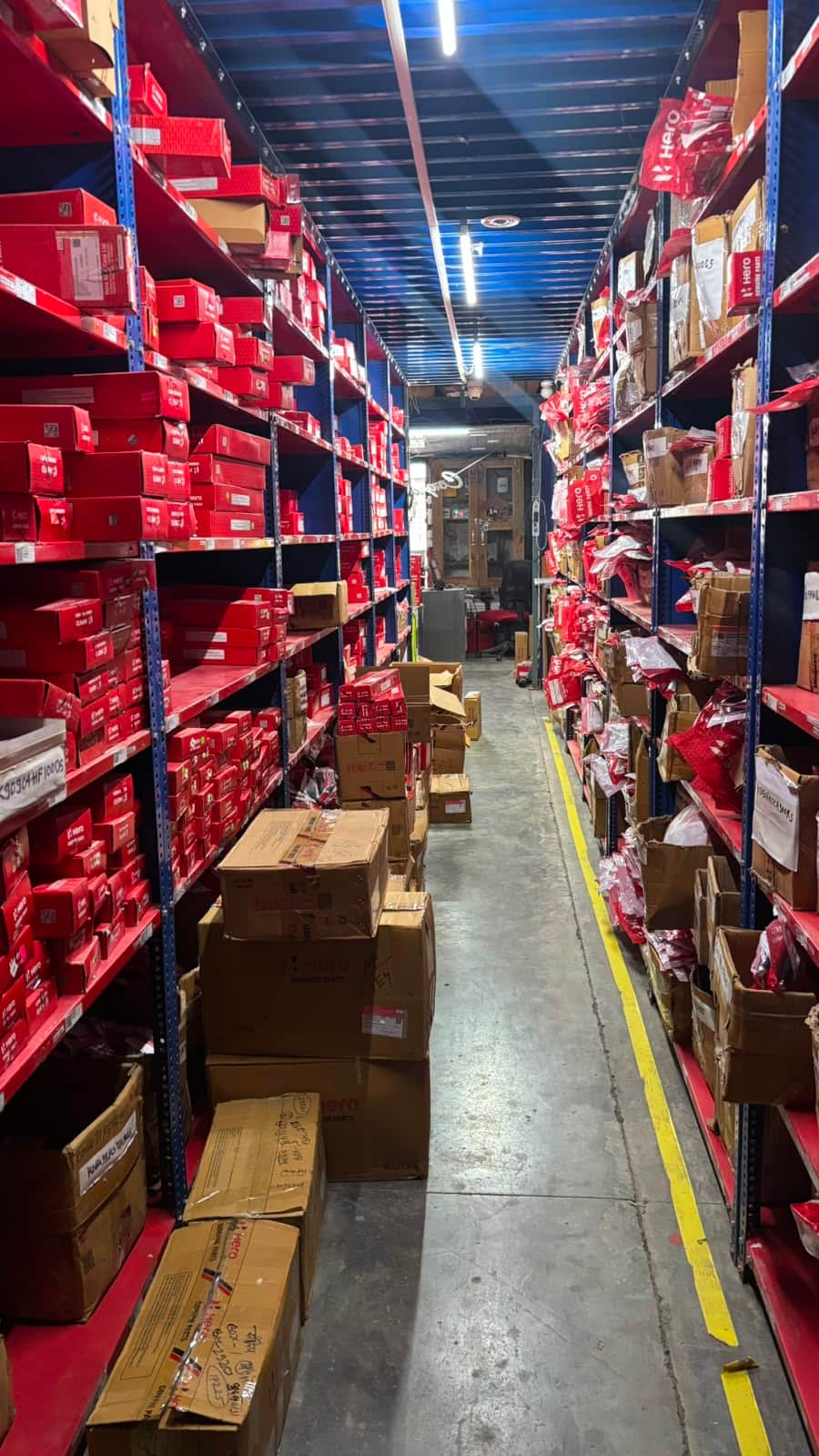 Racked aisle of boxed OEM-pattern motorcycle spare parts ready for export